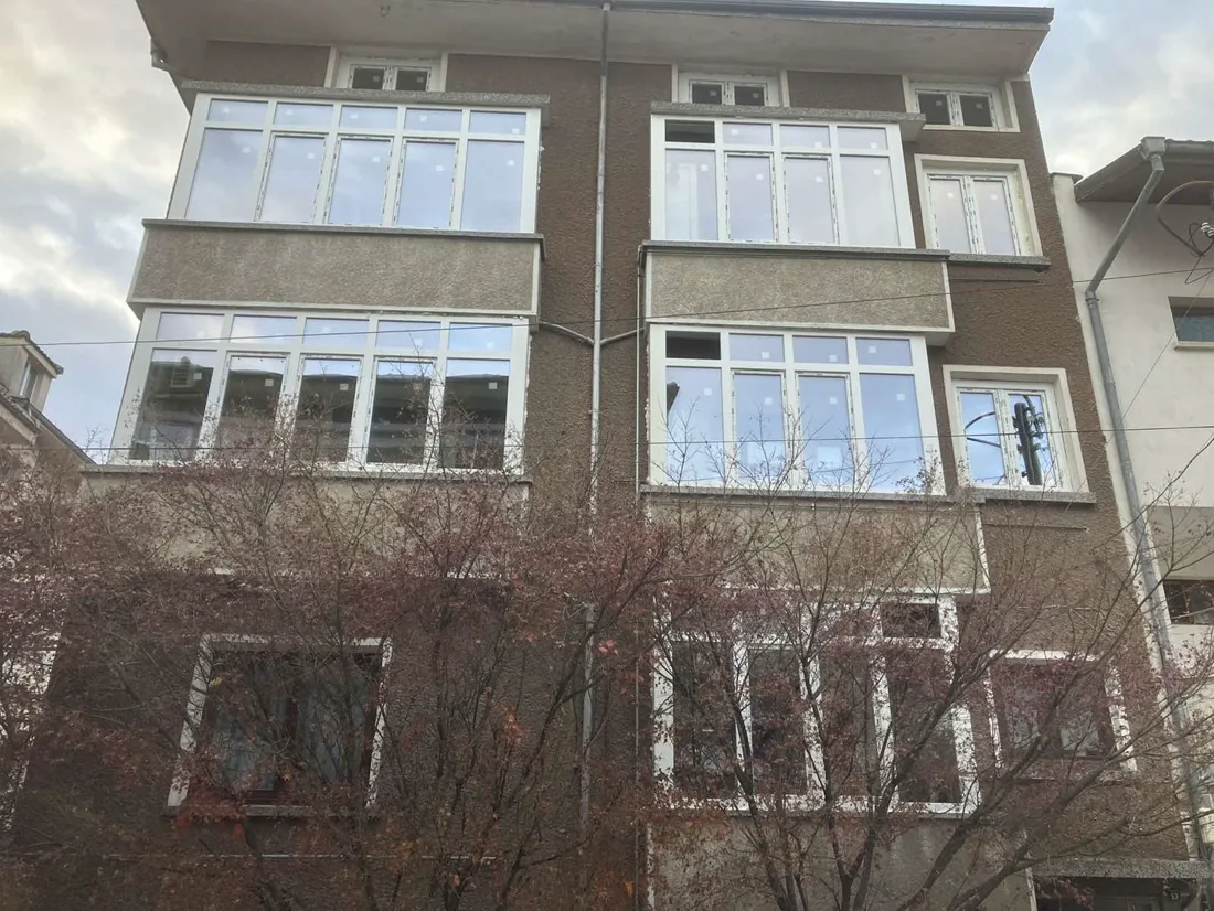 Светлосиви PVC дограма с бели рамки на многоетажна сграда.